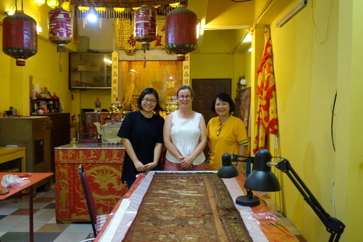 Kristin Phillips (centre) with Annie Lee & Miki Tempo from George Town World Heritage Inc. Textile Conservation Capacity Training for the local Community in George Town Malaysia, Nine Emperor Gods Banner, Kew Ong Yeh Temple, Hong Kong Street.