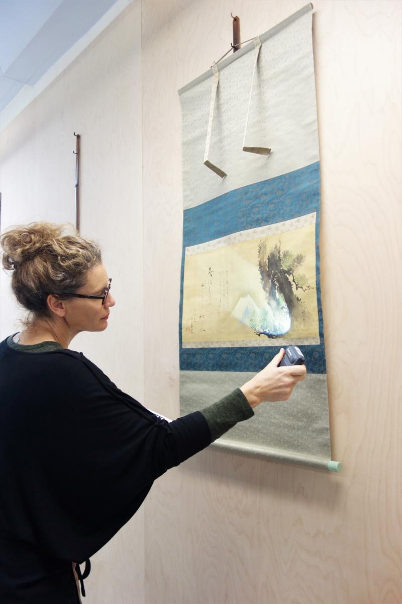 Louise Wilson condition checking the Hokusai scroll Mt Fuji and the old pine, 1802, in the NGV Paper and Photographs Conservation studio.