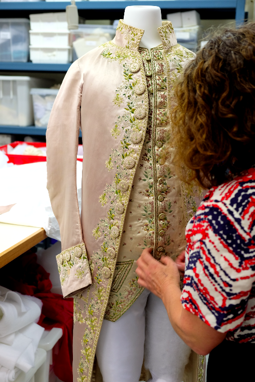Textiles diplay technician Ellen Doyle dressing the mannequin in the 18th-century male outfit.