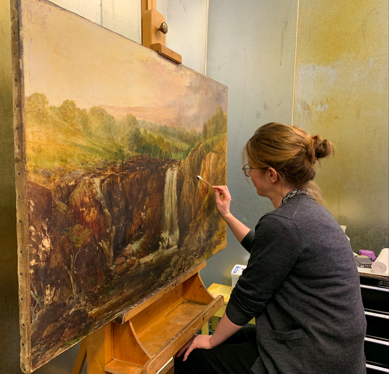 Caitlin Breare, Paintings Conservator, working on her detailed treatment of collection item Thomas Clarke’s The Upper Falls on the Wannon (1867).
