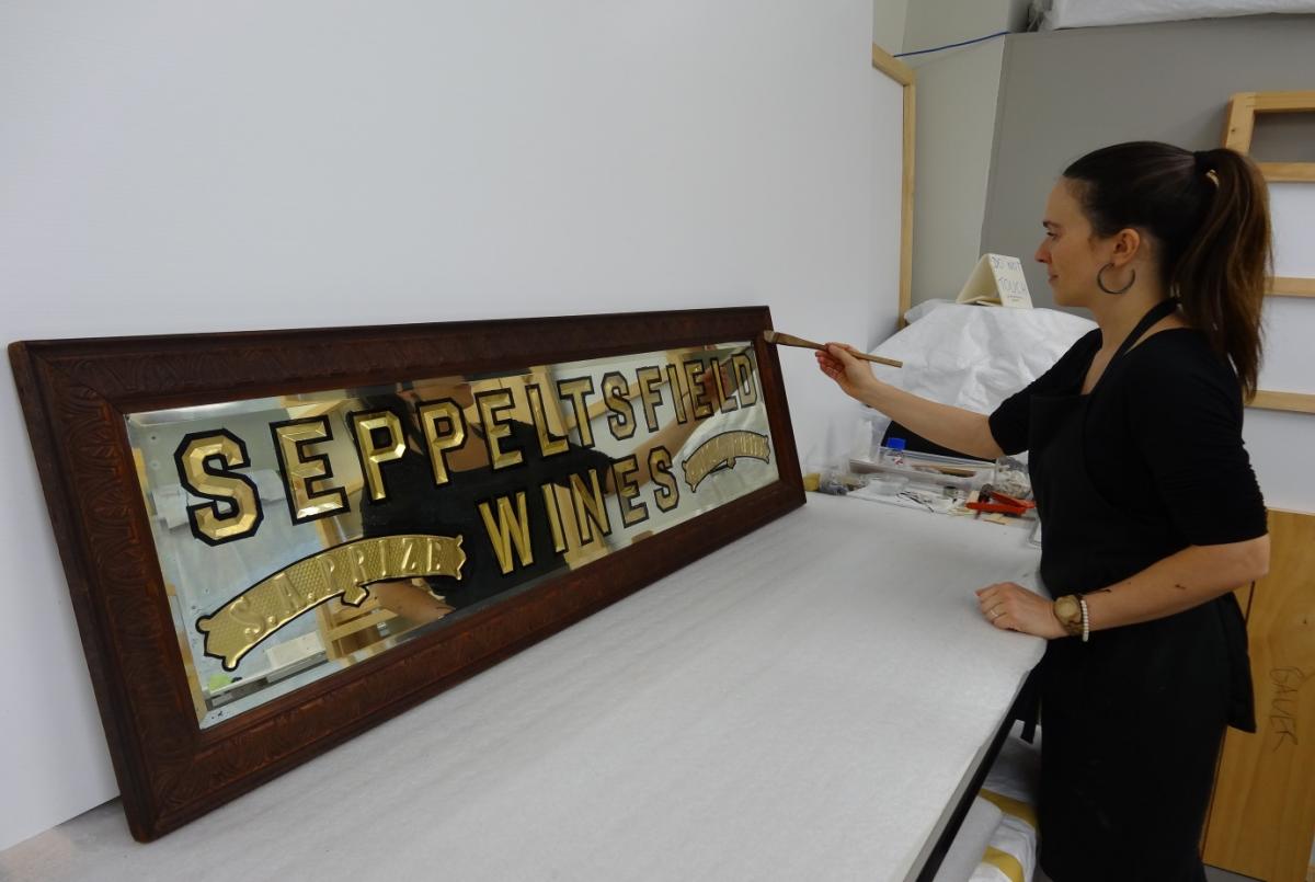 During and after images of Filipa Quintela’s gilding treatment of a Seppeltsfield Wines advertising sign.