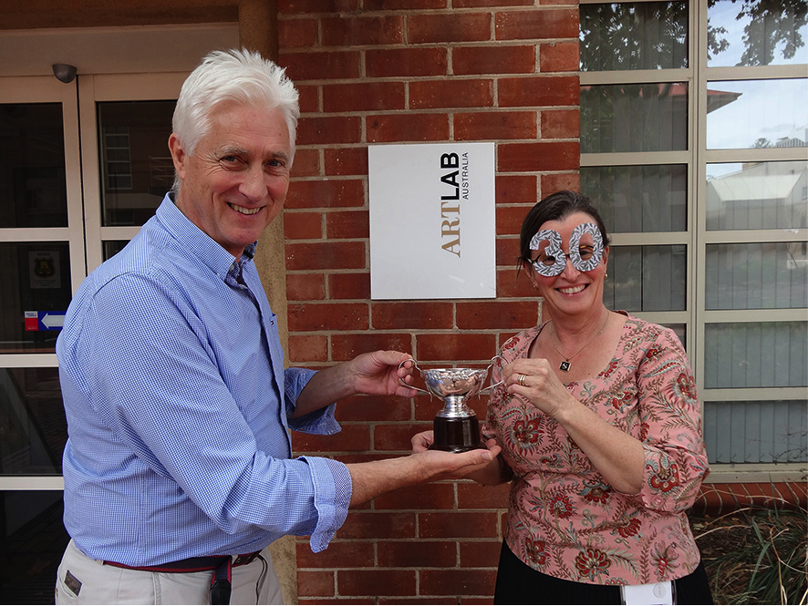 Artlab Director Andrew Durham presenting Principal Textiles Conservator Kristin Phillips with the Artlab “30” Trophy.