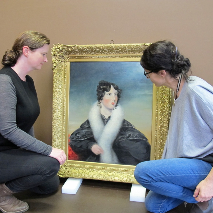 Jennifer O’Connell and Lisa Charleston examining a recent donation, a very fine portrait by Benjamin Duterrau.