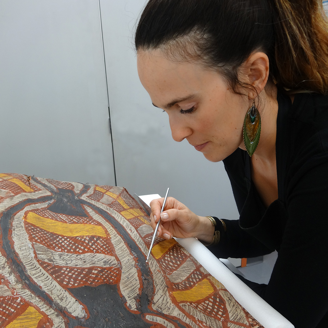 Filipa consolidating paint flakes on a Tunga from Melville Island, Northern Territory, South Australian Museum collection, A47049. Image: Artlab Australia