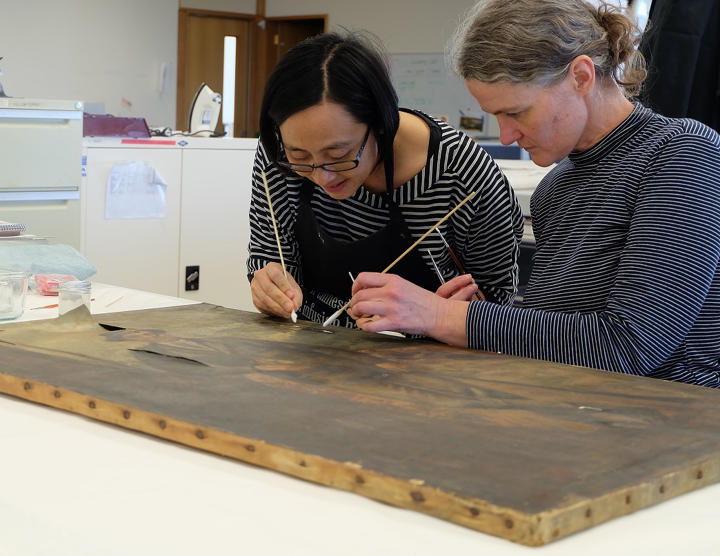 Lisa Jeong-Reuss and Janet McDonald tackled cleaning and tear repairs for a 19th century bushranger portrait. Image: Freya Merrell