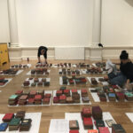 Conservators working on floor surrounded by stacks of books
