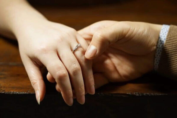 Two people's hands held to show off engagement ring