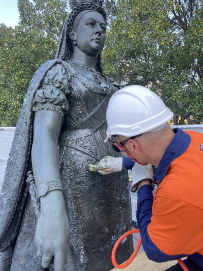 Mathew applying wax coating to Queen Victoria sculpture.