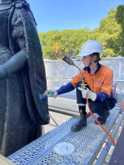 Emily applying wax coating to Queen Victoria sculpture.